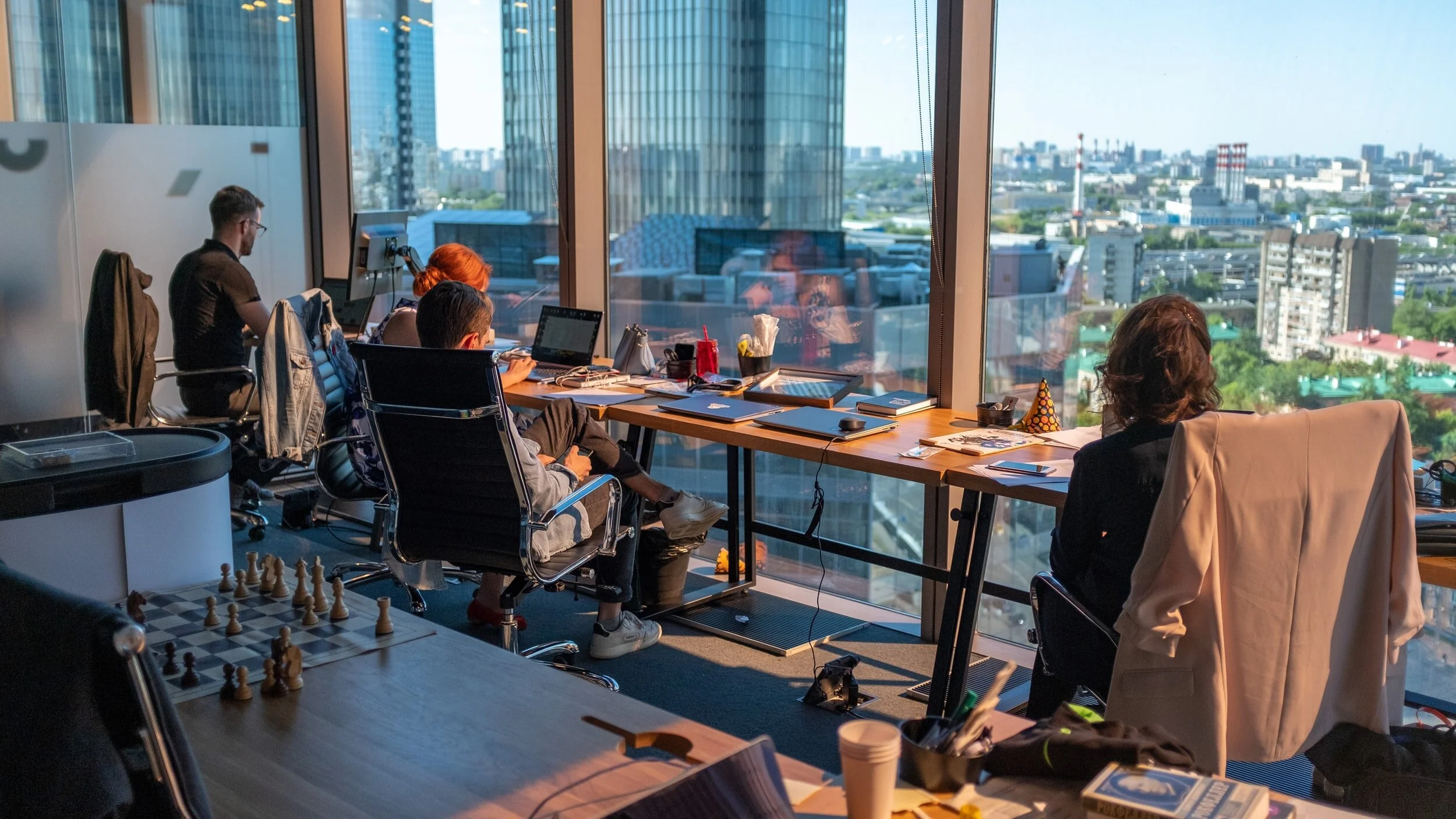 A team working at desks by a wall of windows over a city skyline